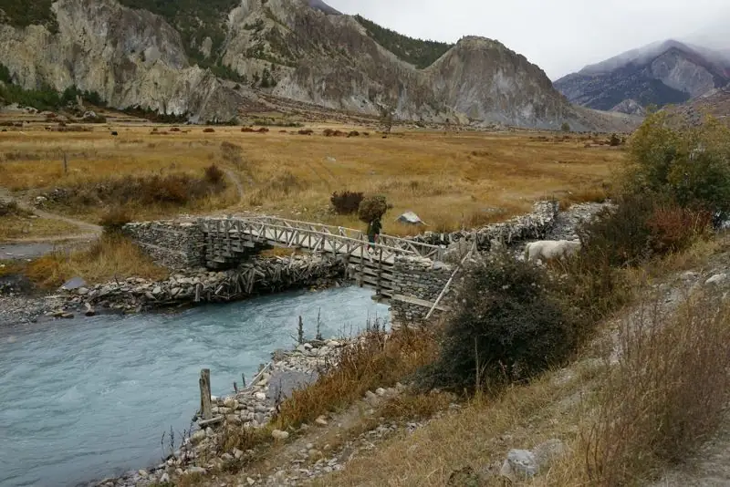 Arid Himalayan valley with a wooden bridge over a river