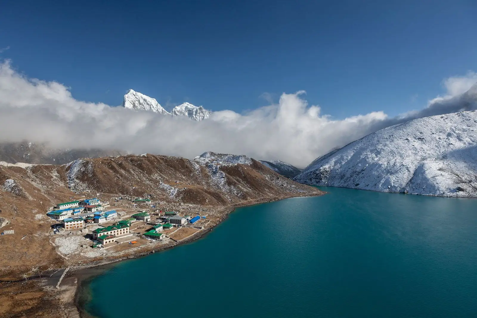 Lakeside settlement beside a deep blue glacial lake and glaciated peaks