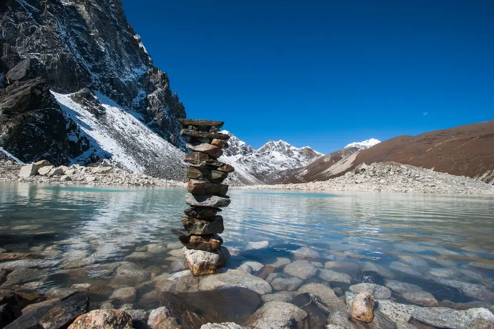Stacked stones in shallow clear water at a sacred lake near Gokyo
