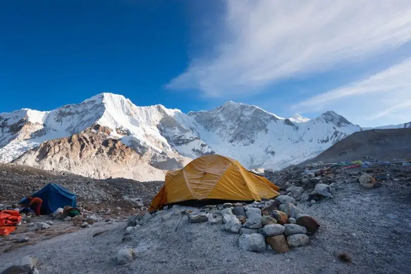 Tents pitched at a high camp below glaciated peaks