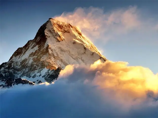 Machhapuchhre peak in golden sunset light above the clouds